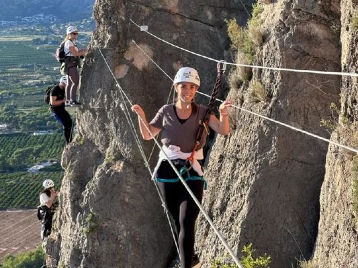 Participante cruzando un puente tibetano durante una vía ferrata en Alicante