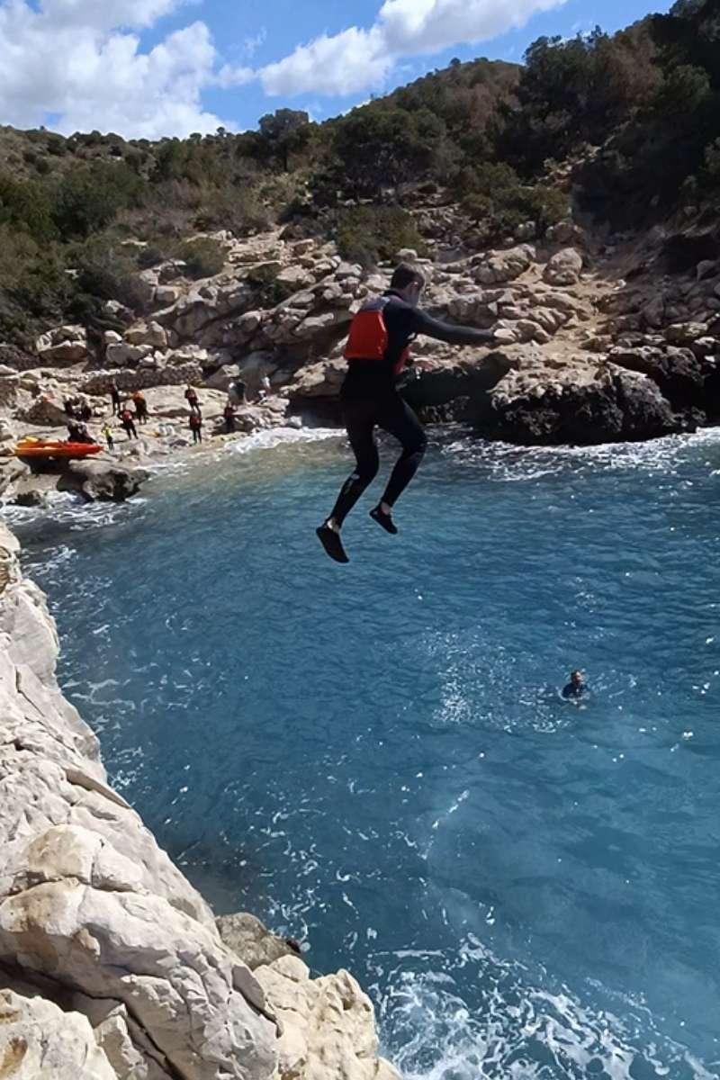 Participante realizando un salto al mar durante la ruta en kayak hasta la Torre del Aguiló