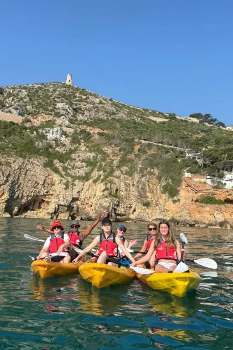 Grupo disfrutando de una ruta en kayak con la torre del Cabo de Sant Antoni al fondo entre Dénia y Jávea