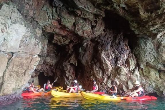 Grupo explorando una cueva marina en kayak durante la ruta por el Cabo de Sant Antoni