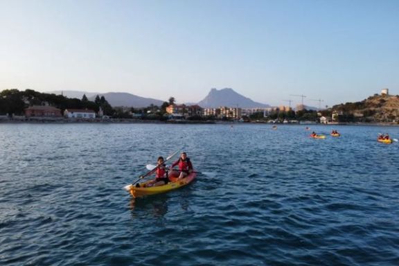 Participantes navegando en kayak frente a la costa de Villajoyosa al caer la tarde