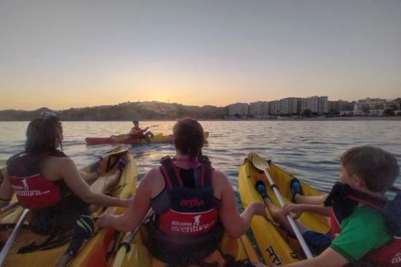 Familia disfrutando de la ruta nocturna en kayak durante el atardecer