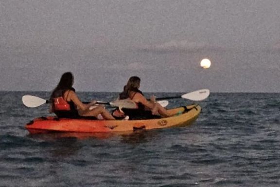 Dos participantes navegando en kayak bajo la luz de la luna frente a la costa de Villajoyosa