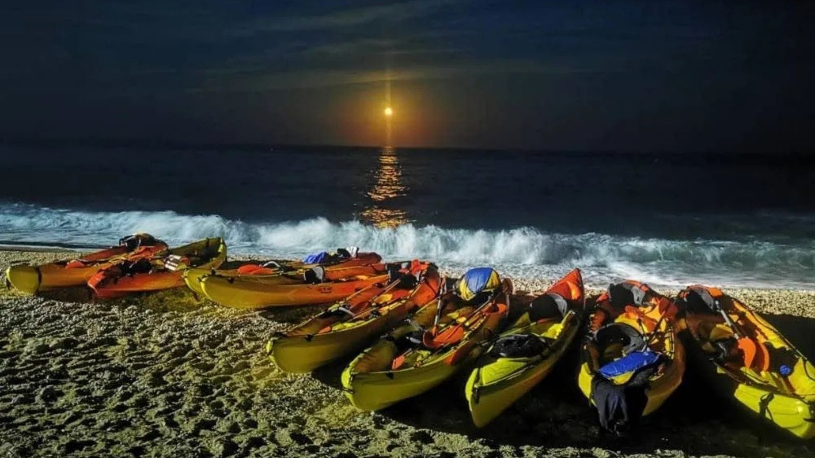 Kayaks en la playa bajo la luz de la luna durante la ruta nocturna por la costa de Villajoyosa