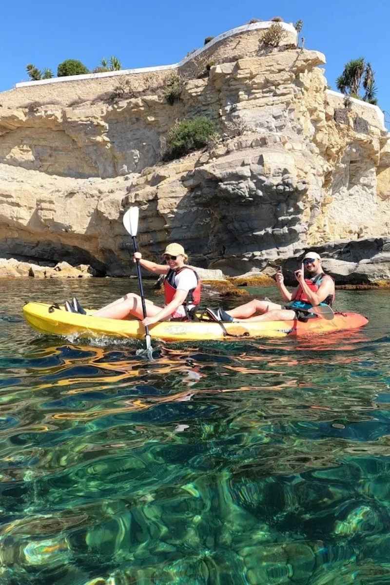 Pareja disfrutando de la ruta en kayak por la costa de Moraira junto a los acantilados de Cap Blanc