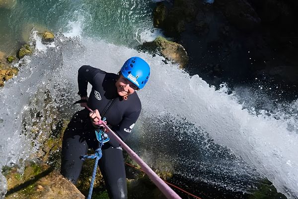 Barranquismo en Alicante y Valencia con participante descendiendo en rápel junto a una cascada