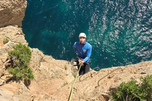 Escalador con casco y cuerda visto desde arriba en una pared del Morro de Toix